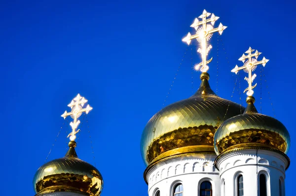 Russian church with golden dome and cross on the top close up. Golden dome and cross on the top against background of blue sky