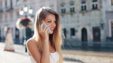 Günbatımı yürüme çekici esmer kadın sokak aşağı ve smartphone ile konuş. Mutlu kız Smartphone konuşmak yürüme şehirde