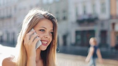 Günbatımı yürüme çekici esmer kadın sokak aşağı ve smartphone ile konuş. Mutlu kız Smartphone konuşmak yürüme şehirde