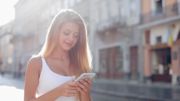 年轻女子使用智能手机行走在美丽的欧洲城市。慢动作。女孩浏览互联网, 寻找地图和信息, 交流。旅行 — 图库视频影像