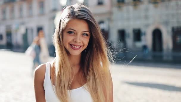 Portrait of beautiful young woman with with blue eyes and attractive smile. She stands in the middle of the street of a beautiful European city — Stock Video