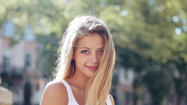 Gyönyörű fiatal nő, vonzó mosolyt és kék szeme portréja. Ő áll gyönyörű európai város az utca közepén. Napfény — Stock videók