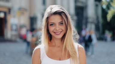 Güzel bir genç kız içine belgili tanımlık fotoğraf makinesi ve gülümseyen, mutlu yüz arıyorum portresi. Lüks beyaz elbise giymiş kadın çok büyüleyici bir Avrupa şehri sokakta duruyor. Ağır çekim