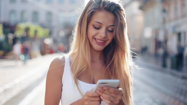 Mujer joven usando smartphone en la ciudad europea. A cámara lenta. Hermosa chica navegando por Internet, buscando mapas e información, comunicándose. Viajes — Vídeo de stock