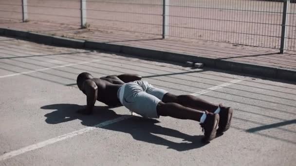 Атлетичный афроамериканец отжимается. Кросс-тренировка. Тренировки, фитнес, бег, мотивация . — стоковое видео