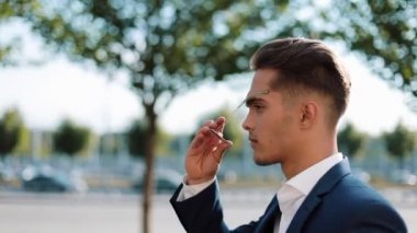 Genç adam sokakta yürürken güneş gözlüğü takıyor. Başarılı bir hayat. İş tarzı, Gezgin, iletişim, modern yaşam tarzı. Aktif yaşam tarzı