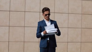 Genç işadamı belgeleri ve komik Ofis Binası yakınındaki dans atar. Ağır çekim video. Mavi elbiseli bir adam