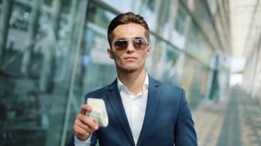 Büyük miktarda para onun elinde tutan genç iş adamı. Ofis merkezi veya banka yakınlarında sokakta duruyor. İş tarzı, kazanç, para, başarı, kariyer