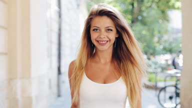 Sevimli genç kadın ile bir güzel beyaz bir elbise içinde bağsız kıl genç kadınla sokakta yürürken, kamera gülümsüyor arıyorum. Sabit cam vurdu, ağır çekim