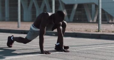Atletik Afrikalı-Amerikalı adam hızlı bir şekilde spor stadyum yakınında sokakta açık tahta içinde bacaklarını kır. Fitness, sağlık, spor, vücut geliştirme, aktif yaşam tarzı