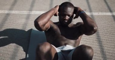 Atletik Afrikalı-Amerikalı adam sokakta bir gri mat egzersizi yapıyor. Sağlık ve fitness kavramı. 4k, gerçek zamanlı vurdu