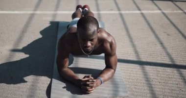 Bir tahta sokak eğitim, performans atletik Afrikalı-Amerikalı adam. Genç spor adamı egzersiz Spor Stadyumu yakınındaki egzersiz adam. Çapraz uygun eğitim. Kaslı zenci adam açık iterek