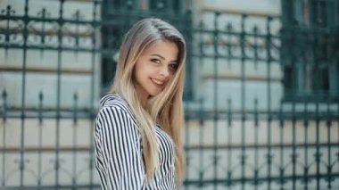 Eski sokakta yürürken güzel elbiseli mutlu güzel kadın. Ağır çekim. şık bir görünüm. Çekici genç hanım şehir merkezinde yürüyor, kamera ve gülümsüyor ortaya