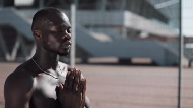 Afrikalı-Amerikalı adam sokakta Tanrı'ya dua ve kameraya bakıyor. İnanç, din, yoksulluk, hapishane kavramı. Ağır çekim, steadycam vurdu