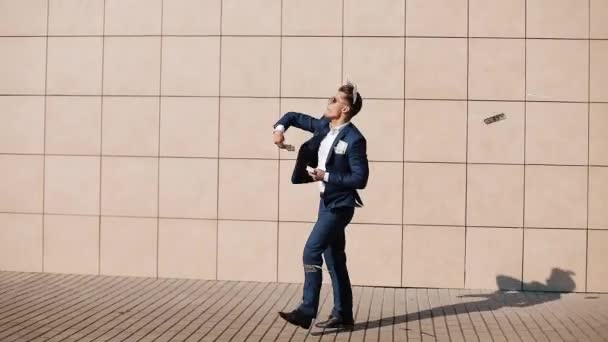 Young happy businessman scatter the dollars and dancing in the street. It is located near the office center, slow motion. Successful business — Stock Video