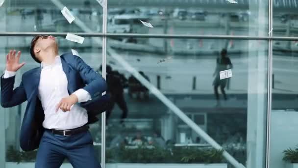 Lluvia de dinero cae del cielo, un joven atrapa dinero. Joven hombre de negocios con paquetes de dinero en dólares. Concepto de negocio, personas y finanzas y pérdida de dinero — Vídeo de stock