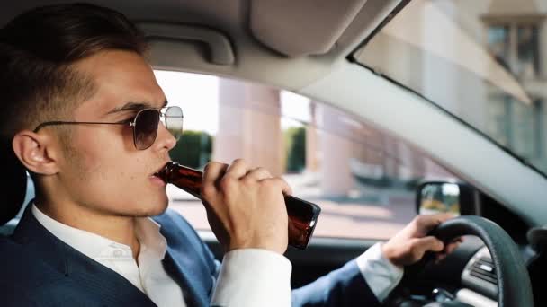 Młody biznesmen picia piwa w samochodzie. Człowiek w zły nastrój z powodu zły interes lub złe wieści. Pijane, jazdy i nieudanych biznes koncepcja — Wideo stockowe