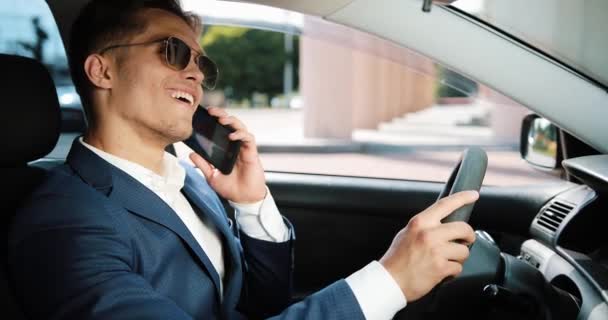 Молодой счастливый бизнесмен разговаривает по смартфону, сидя в машине. Концепция бизнеса, людей, коммуникаций, успеха и финансов — стоковое видео