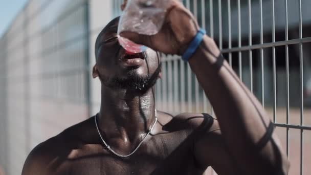 黑人疲惫的非洲裔美国男性运动员经过刻苦训练, 喝干净的冷水, 倒在他的头上, 慢动作。交叉配合训练 — 图库视频影像