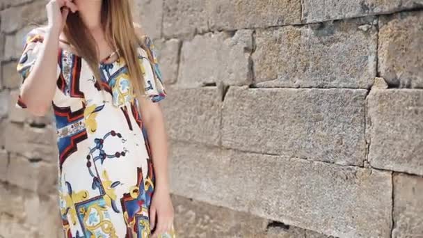 Aantrekkelijke jonge vrouw in een mooie zomerse jurk staande in de straat van een Europese stad, glimlachen en kijken naar de camera. Portret mooi meisje in de stad — Stockvideo
