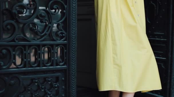 Sarı bir seksi elbiseli bir Avrupa şehri Caddesi üzerinde duran ve kameraya doğru seyir çekici bir genç kadın portresi. Doğal güzellik, kadın portre, baştan çıkarıcı bir görünüm. — Stok video