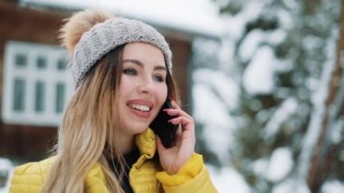 Gülümseyen kadın konuşuyor telefonda ayakta dışında arka bahçeye düşen kar altında. Kır evi bir kış ceket giyen kadın. İletişim, seyahat, bir yaşam tarzı kavramı. Kırmızı Epic vurdu