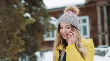 Gülümseyen kadın konuşuyor telefonda ayakta dışında arka bahçeye düşen kar altında. Kır evi bir kış ceket giyen kadın. İletişim, seyahat, bir yaşam tarzı kavramı. Kırmızı Epic vurdu
