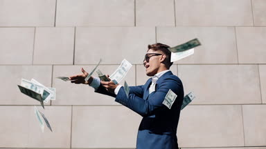 Mutlu genç işadamı dağılım dolar ve komik sokakta dans. Para yağmur, düşen dolar. Bu office center yanında, ağır çekim yer almaktadır. Başarılı bir iş. Kırmızı Epic vurdu