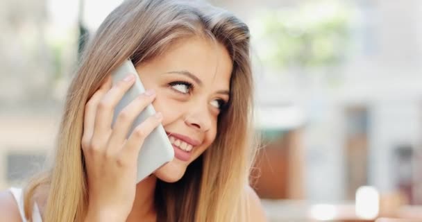 Encantadora mujer joven hablando ensmartphone sentado en la cafetería. Comunicación, descanso, turismo, estilo de vida. Hora de verano. Dispara en RED Epic — Vídeos de Stock