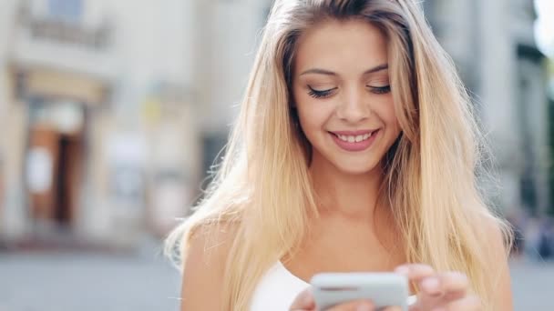 Hermosa mujer joven utilizando la aplicación de tecnología de teléfonos inteligentes en las calles de la ciudad vieja. Comunicación, tecnología, estilo de vida. Marco vertical para dispositivos móviles — Vídeos de Stock