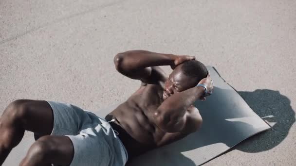 L'homme athlétique afro-américain fait des craquements sur un tapis gris dans la rue. Concept de santé et de fitness. 4k, plan en temps réel — Video