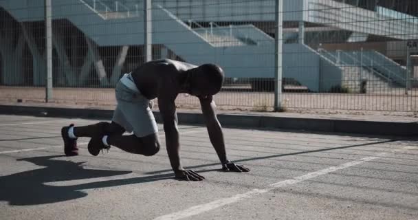 Homme afro-américain athlétique rapidement plier les jambes dans la planche avant dans la rue près du stade de sport. Fitness, santé, sport, musculation, mode de vie actif — Video