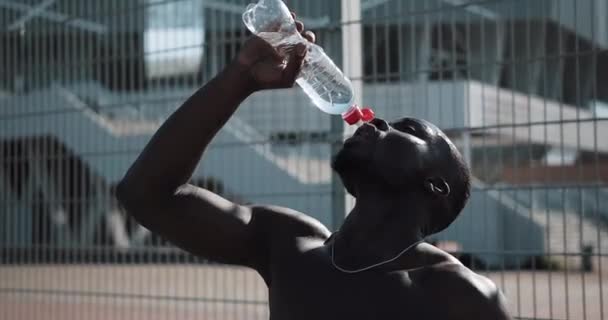 Preto cansado atleta masculino afro-americano após o treinamento duro beber água fria limpa. Treinamento cross fit — Vídeo de Stock