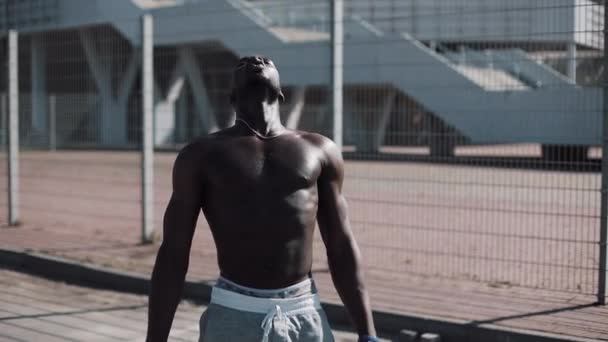 Соблазнительный афроамериканский спортсмен восстанавливает силы после тяжелой тренировки на открытом воздухе. Motivation, pumping body, sports, gym, success, street workout, muscles. Shot on Red Epic — стоковое видео