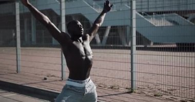 Afro-Amerikan erkek athlet sabah egzersiz açık havada yakın yavaş hareket güneş kadar yapar. Egzersiz ayakta Spor Stadyumu yakınında sokakta. Sağlıklı yaşam irade motivasyon kavramı