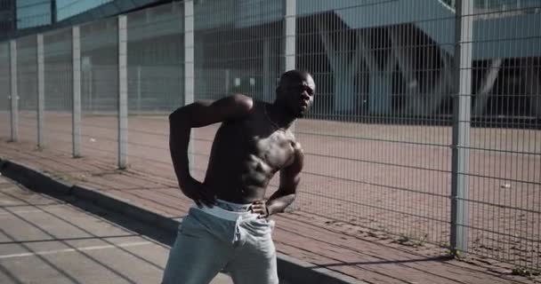 非洲裔美国人男性运动员做早操在户外关闭慢动作太阳照耀。健身站在体育场附近的街道上。健康的生活方式将动力激励理念 — 图库视频影像