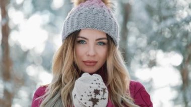 Güzel kadın ayakta dışında ormanda kar kış şapka gülümsüyor. Kameraya bakarak bir güzel kız portresi. Kış saati dinlenme, kış bayramlar, yılbaşı, tatil