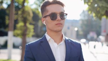 Çekici genç işadamı dışında yürüyüş kablosuz kulaklık kullanarak telefonda konuşuyor. Mutlu bir adam görüşmeler. İletişim, finans, iş adamları, stajyerler, Ceo. Yakın çekim. Kırmızı Epic vurdu