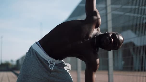 Afrikanisch-amerikanischer männlicher Athlet macht Morgengymnastik im Freien in Zeitlupe. Training auf der Straße in der Nähe des Sportstadions. Gesunder Lebensstil stärkt Motivationskonzept — Stockvideo