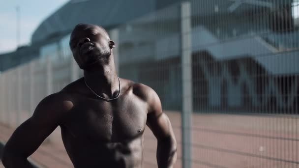 Athlet mâle afro-américain fait l'exercice du matin à l'extérieur fermer au ralenti soleil briller. Entraînement debout dans la rue près du stade de sport. Style de vie sain va pouvoir concept de motivation — Video