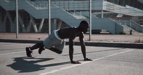 Der athletische afrikanisch-amerikanische Mann beugte auf der Straße in der Nähe des Sportstadions schnell die Beine vor die Planke. Fitness, Gesundheit, Sport, Bodybuilding, aktiver Lebensstil — Stockvideo