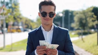 Güneş gözlüğü ve para sayma ve sokakta yürürken bir takım elbise genç mutlu businesman. O selebrating ile dolar bir çok kazanmak onun başarılı