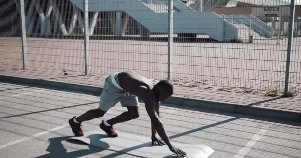 Streetworkout. athletischer afrikanisch-amerikanischer Mann, der Liegestütze macht und sich im Freien dreht. Ein schwarzer Mann treibt in der Nähe des Stadions Sport. Training, Fitness, Laufen, Motivation — Stockvideo