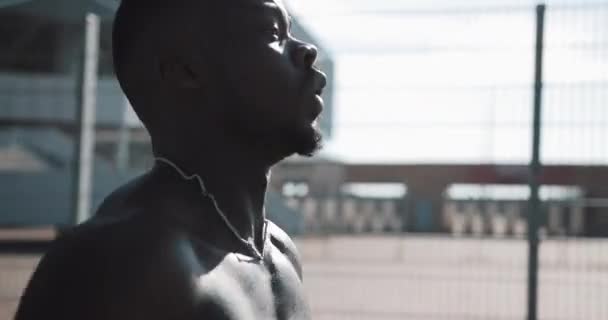 El atleta afroamericano hace ejercicio matutino al aire libre cierra el brillo del sol en cámara lenta. Entrenamiento de pie en la calle cerca del estadio deportivo. Estilo de vida saludable voluntad poder motivación concepto — Vídeo de stock