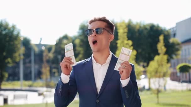 Happy young businessman holding a big amount of money in his hands and funny dancing. Business style, winning, deposit, success, career. Shot on Red Epic — Stock Video
