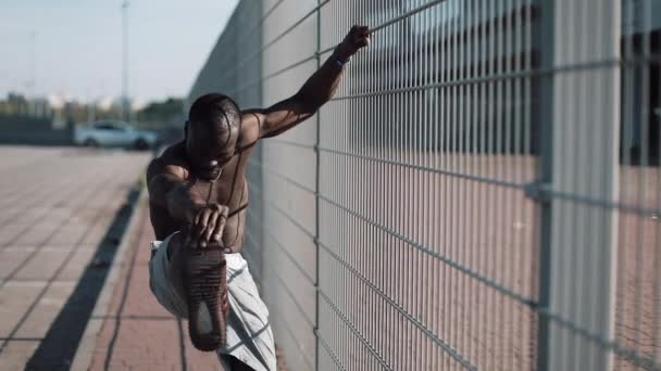 Afro-americano atleta masculino faz exercício matutino ao ar livre fechar o sol de câmera lenta brilhar. Treino em pé na rua perto do estádio de esportes. fitness estilo de vida saudável irá impulsionar o conceito de motivação — Vídeo de Stock