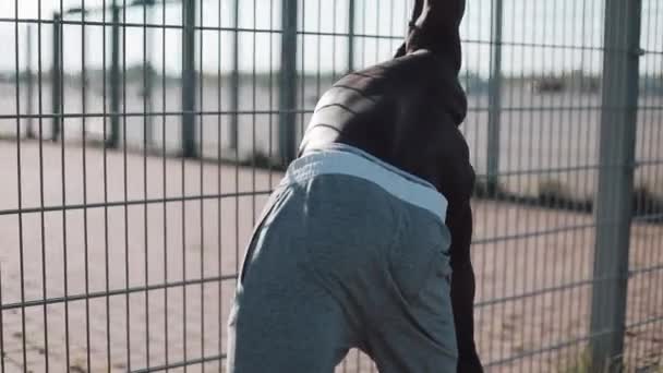 African American athlet mężczyzna robi rano ćwiczenia na zewnątrz Zamknij się powolny ruch słońca blask. Ćwiczenie stojąc na ulicy w pobliżu Stadion sportowy. Zdrowy styl życia będzie moc koncepcja motywacji — Wideo stockowe