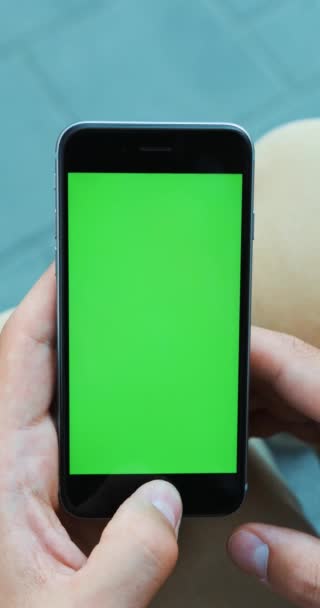 Человек держит в руке смартфон на улице зеленый экран макет chromakey размытие фоне проверки новостей карты уведомлений GPS чата приложения Интернет подключение к Интернету чтение онлайн. Вертикальное видео — стоковое видео