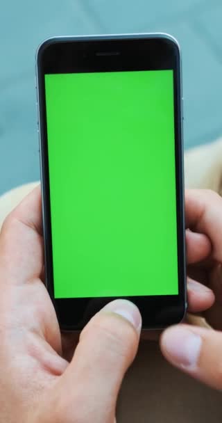 Verticale video. Man hand bedrijf smartphone in de straat groen scherm mockup chromakey vervagen achtergrond controleren nieuws kennisgeving kaart gps apps chatten internetverbinding online lezen — Stockvideo