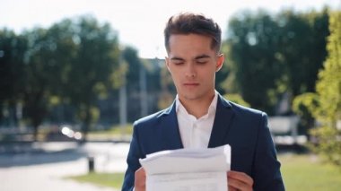 Şık elbiseli ciddi bir genç işadamı gazeteleri dikkatle inceliyor. Başarılı yaşam tarzı, sözleşme, sorumluluk